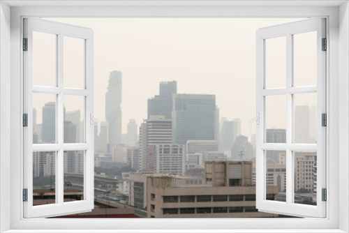 Fototapeta Naklejka Na Ścianę Okno 3D - Air pollution effect made low visibility cityscape with haze and fog from dust in the air during sunset in Bangkok, Thailand. Image contain noise and grain.