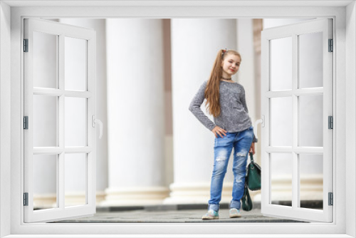 portrait of little beautiful stylish kid girl with umbrella near columns