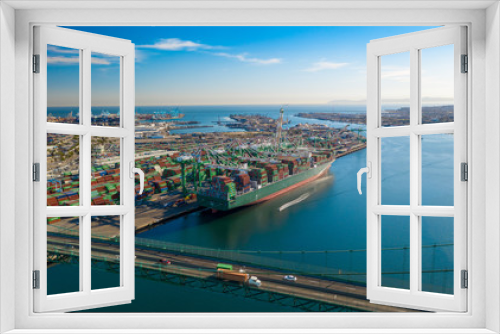 Fototapeta Naklejka Na Ścianę Okno 3D - Aerial view of harbor unloading cargo from a large container ship with cranes from above with transport bridge.