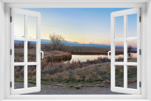 Fototapeta Naklejka Na Ścianę Okno 3D - Views of Josh’s Pond walking path, Reflecting Sunset in Broomfield Colorado surrounded by Cattails, plains and Rocky mountain landscape during sunset. United States.