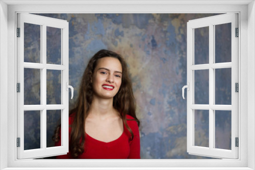 Smyling young girl in a red dress on a dark background