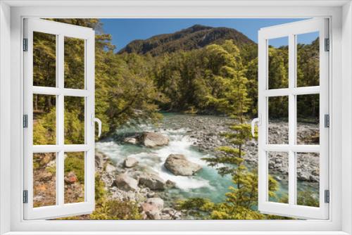 Fototapeta Naklejka Na Ścianę Okno 3D - The crystal clear Route Burn rapidly flowing over large rocks and through the dense rainforest with mountains in the background, Mount Aspiring National Park, New Zealand.