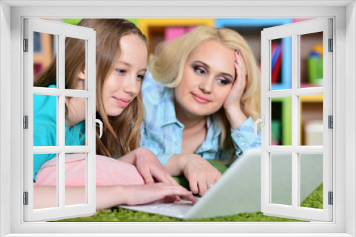 Portrait of young woman with girl using laptop