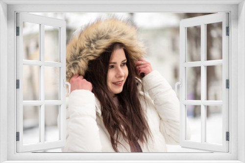 Young beautiful girl in the middle of snowy park. Warm and comfortable winter clothes, winter time