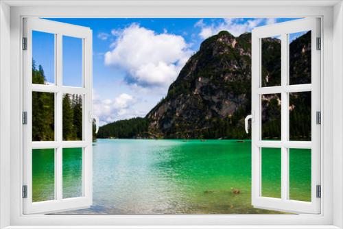 Fototapeta Naklejka Na Ścianę Okno 3D - view of Lago di Braies between the dolomiti mountains, a cloudy summer day, with some boats on the green water, tourism