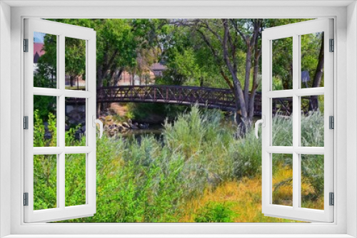 Fototapeta Naklejka Na Ścianę Okno 3D - Views of Jordan River Trail Pedestrian and Train Track Bridge with surrounding trees, Russian Olive, cottonwood and muddy stream along the Wasatch Front Rocky Mountains, in Salt Lake City, Utah.