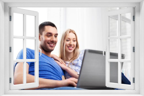 technology, internet and people concept - happy couple with laptop computer at home