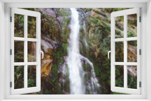 Fototapeta Naklejka Na Ścianę Okno 3D - A waterfall spotted in Tal, Annapurna Circuit Trek, Nepal. Few hundred meters of free fall, waterfall surrounded by tall mountains slopes, covered with green bushes and trees. Smooth capture