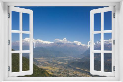 Fototapeta Naklejka Na Ścianę Okno 3D - city in a green mountain valley on the background of the Annapurna snow ridge under a clear blue sky