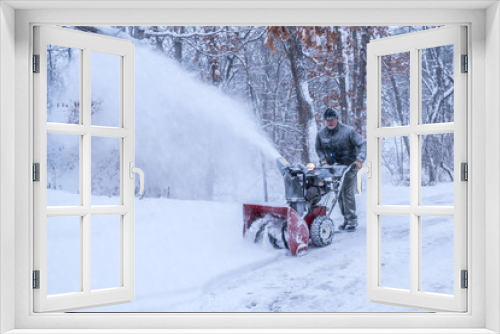 Fototapeta Naklejka Na Ścianę Okno 3D - An old white man is using snow blower to plow / blow snow 