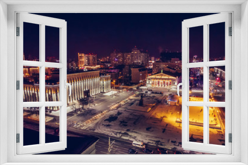Fototapeta Naklejka Na Ścianę Okno 3D - Public ice rink with skating people in city near asphalt road with cars in center or downtown of illuminated winter Voronezh, Russia, aerial view