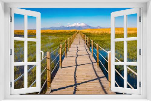 Fototapeta Naklejka Na Ścianę Okno 3D - Wooden bridge walkway path on marshes and reeds in front of mountain. This is from Sultan Sazligi and Erciyes Mountain in Kayseri Turkey. Pastoral beautiful landscape background. 