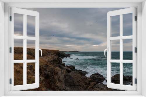 Fototapeta Naklejka Na Ścianę Okno 3D - sea ​​scenery in dramatic weather in the blue hour. a landscape with dramatic clouds and stormy water that breaks down on the shore and the rocks.