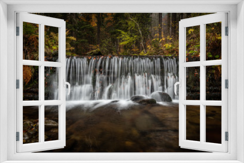 Fototapeta Naklejka Na Ścianę Okno 3D - Autumn in forest by a river. A special and magical scene, fallen leaves, dark tones and flowing water. Time and place to relax and unwind. Beautiful time of the year, very popular season.