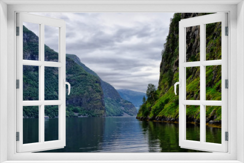 Fototapeta Naklejka Na Ścianę Okno 3D - Holy grail illustrated from Sognefjord or Sognefjorden created from mountain range with blue sky and reflection in clear water and having a wooden dock point out in a river in Flåm