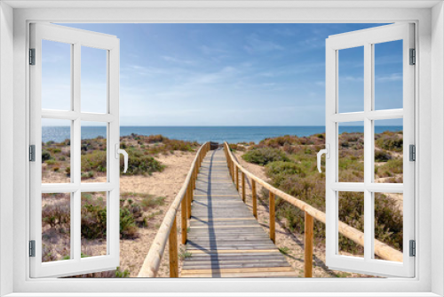 Fototapeta Naklejka Na Ścianę Okno 3D - Wooden pathway over dunes and pines at beach in Punta Umbria, Huelva. Los Enebrales beach
