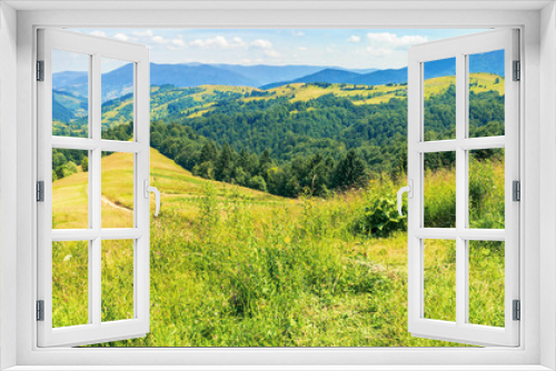 Fototapeta Naklejka Na Ścianę Okno 3D - mountainous countryside on a hot summer afternoon. panoramic landscape, path through grassy slope. meadows on the distant rolling hills. village in the far away valley. sunny weather