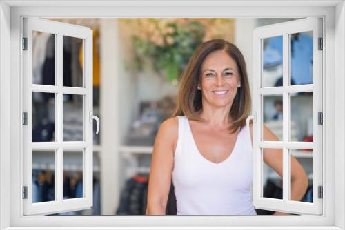 Beautiful middle age hispanic woman standing with smile on face at clothes store. Shop owner and shop assistant smiling confident and cheerful