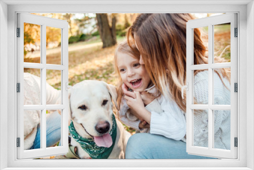 Fototapeta Naklejka Na Ścianę Okno 3D - Happy beautiful family with dog labrador is having fun  are sitting on green grass in park.