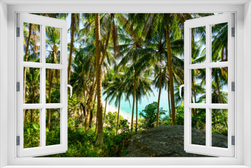 Fototapeta Naklejka Na Ścianę Okno 3D - (selective focus) Stunning view of a paradisiacal beach seen through a rich and green vegetation of palm trees with white sand, people sunbathing and turquoise clear water. Surin Beach, Thailand.
