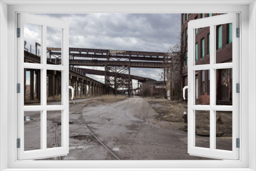Fototapeta Naklejka Na Ścianę Okno 3D - Crossing elevated train tracks and vintage red brick abandoned factory