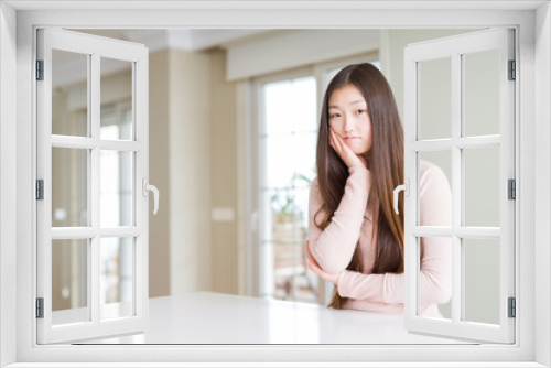 Beautiful Asian woman wearing casual sweater on white table thinking looking tired and bored with depression problems with crossed arms.