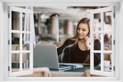 Beautiful girl working out a plan of the project and concept. Girl paints a website design on a laptop. student prints a message on the phone in the messenger. Development. Digital marketing