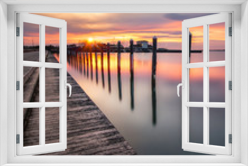Fototapeta Naklejka Na Ścianę Okno 3D - Sunset over an empty fishing pier and boat basin. Beautiful golden colors reflecting on calm still water. Long Island New York. 