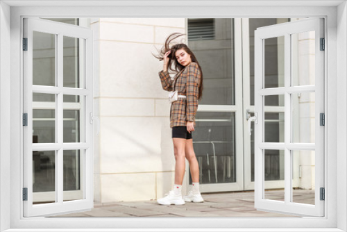 Portrait shooting of a stylish girl. Beige shades. Trends of spring and summer 2019. Wide jacket and belt leather bag. White sneakers and bike shorts