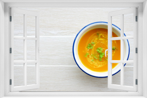 Fototapeta Naklejka Na Ścianę Okno 3D - Pumpkin soup in white bowl with cream and parsley. Light wooden background