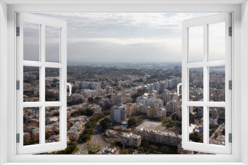 Fototapeta Naklejka Na Ścianę Okno 3D - Aerial view of a residential neighborhood in a city during a cloudy and sunny sunrise. Taken in Netanya, Center District, Israel.