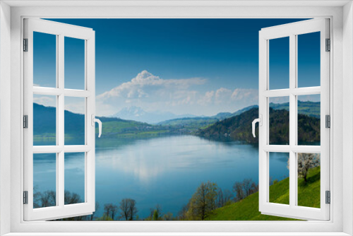 Fototapeta Naklejka Na Ścianę Okno 3D - beautiful panorama lakeside landscape in Switzerland with green fields and blossoming flowers and trees and mountains behind