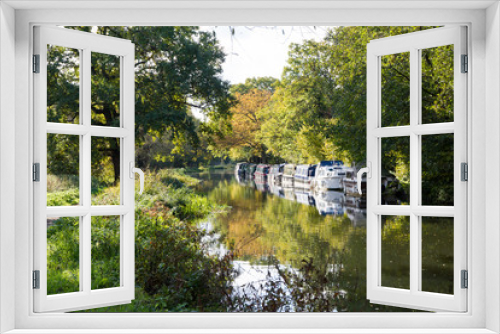 Fototapeta Naklejka Na Ścianę Okno 3D - Canal barges moored against the tree lined bank of the canalised River Wey Navigation on a stretch near Guildford in Surrey woodland