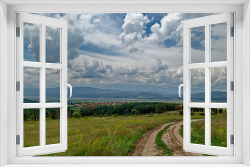 Fototapeta Naklejka Na Ścianę Okno 3D - Springtime scene with glade, forest and residential district of bulgarian village Alino in Plana mountain near Rila  and Verila mountains, Bulgaria 