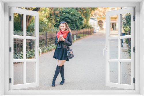 Smiling curvy blond hair woman standing on the street with cup of coffee to go, picture with copy space