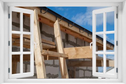 Fototapeta Naklejka Na Ścianę Okno 3D - close up view of scaffolding and house under construction with holders for gutters water drainage system of roof