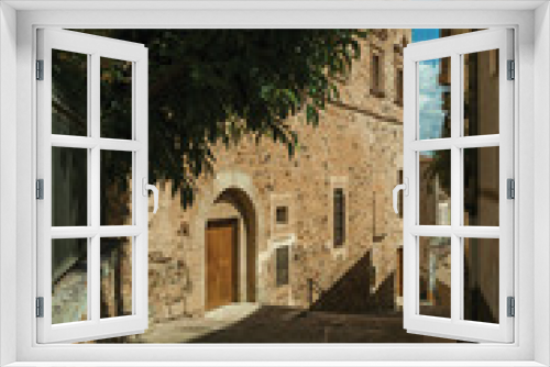 Fototapeta Naklejka Na Ścianę Okno 3D - Alley with staircase amidst old stone buildings and flowering trees at Caceres