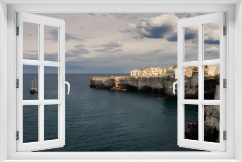 Fototapeta Naklejka Na Ścianę Okno 3D - Un velero bordea la costa de un pueblo blanco de Puglia,  en el Adriático, Italia