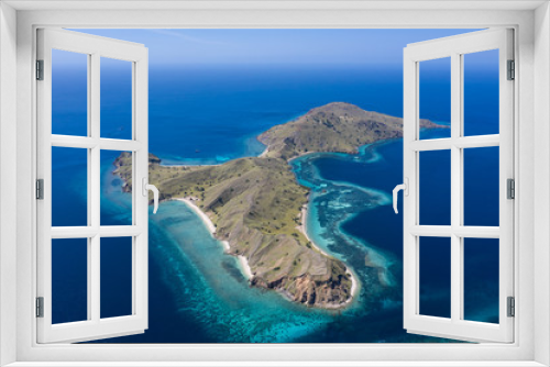 Fototapeta Naklejka Na Ścianę Okno 3D - Seen from a bird's eye view, an idyllic island is surrounded by a healthy coral reef in Komodo National Park, Indonesia. This tropical area is known for its marine biodiversity as well as its dragons.