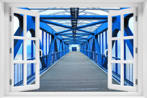 Fototapeta Naklejka Na Ścianę Okno 3D - The prospect of a long corridor of a pedestrian bridge made of bright blue iron construction