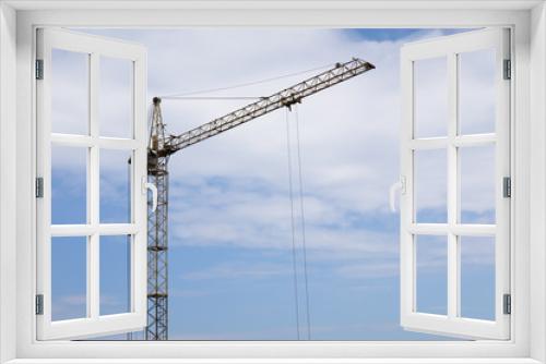 Industrial construction building crane against blue cloudy sky