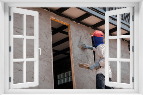 Construction workers plastering building wall using cement plaster