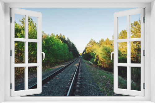 Fototapeta Naklejka Na Ścianę Okno 3D - Scenery with railway in perspective across forest. Journey on rail track. Sleepers and rails. Vanishing perspective. Receding lines. Landscape with railroad along trees. Background with copy space.