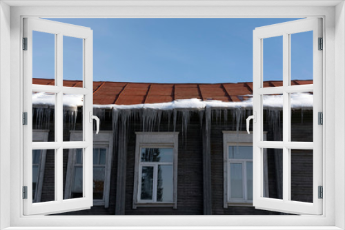Fototapeta Naklejka Na Ścianę Okno 3D - Icicles hang from the roof at the windows of the wooden house - Panorama HDR - High Dynamic Range
