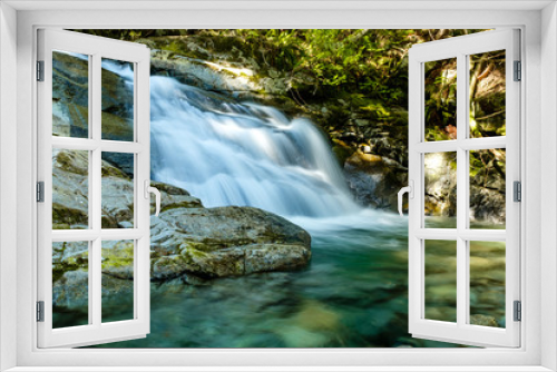 Fototapeta Naklejka Na Ścianę Okno 3D - beautiful waterfall deep inside forest with water running down the creek  surrounded by green trees and moss covered rocks