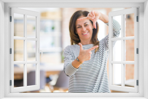 Beautiful middle age senior woman standing smiling making frame with hands and fingers with happy face. Creativity and photography concept.