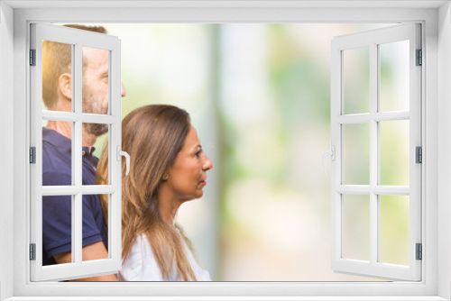 Middle age hispanic casual couple over isolated background looking to side, relax profile pose with natural face with confident smile.