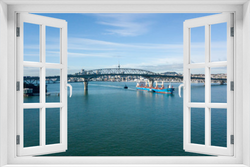 Fototapeta Naklejka Na Ścianę Okno 3D - cargo ship travelling pass Auckland Harbour Bridge, with Auckland City as background