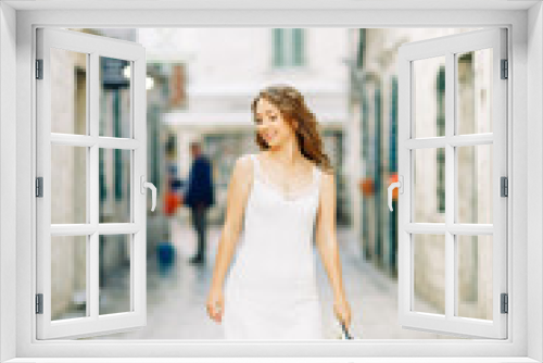 Summer photo shoot on the streets of Kotor, Montenegro. Beautiful girl in white dress and hat.