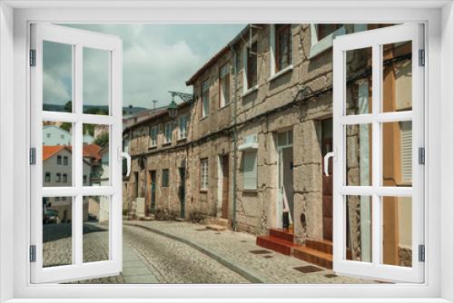 Fototapeta Naklejka Na Ścianę Okno 3D - Old houses with stone wall in a deserted alley